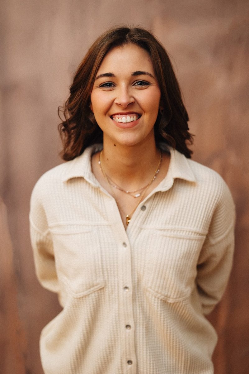 A smiling woman poses in front of a wall.